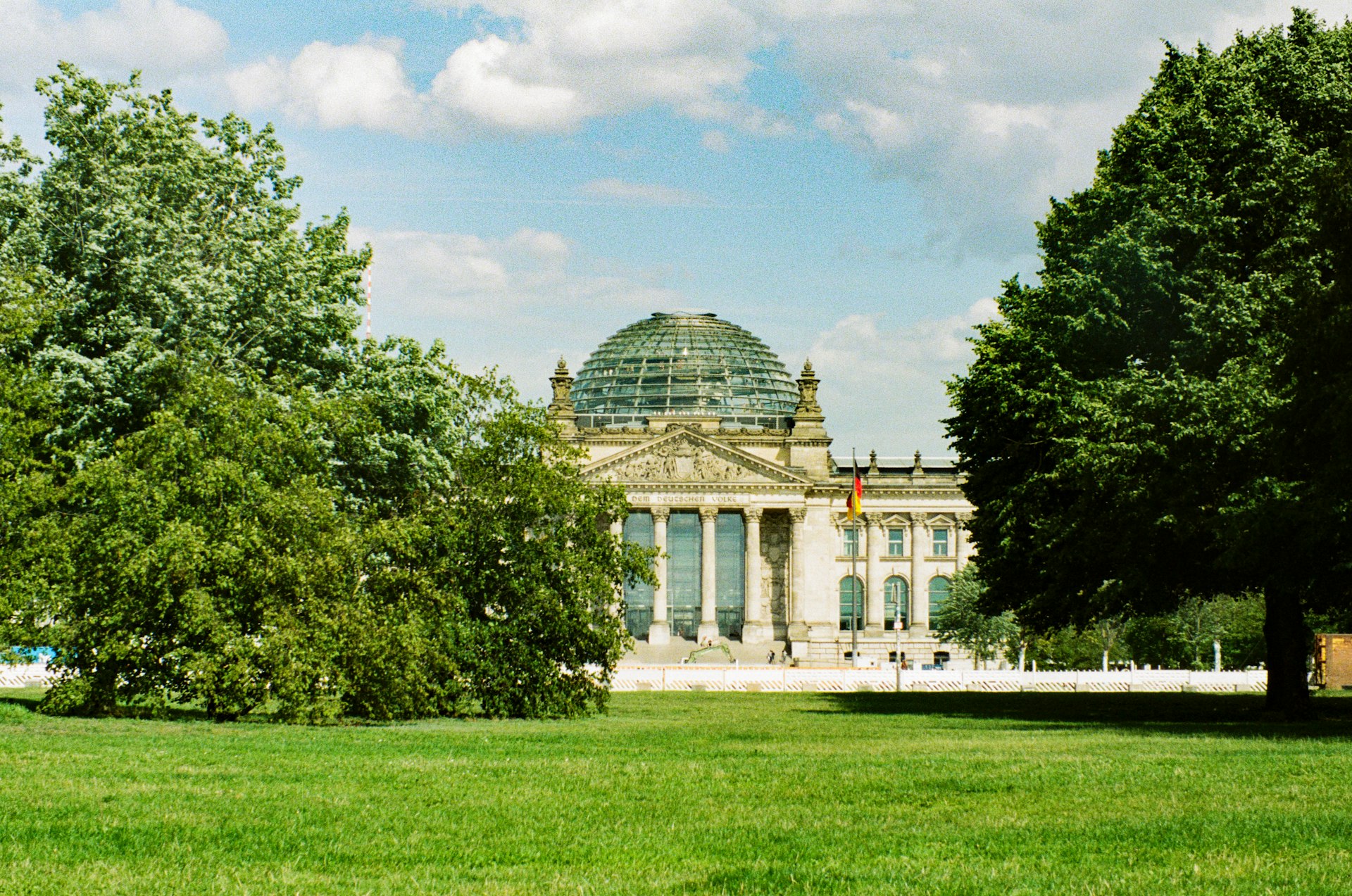The reichstag building is seen through the trees.